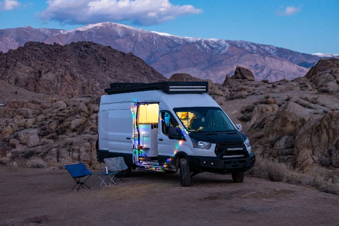 a van parked in the desert with mountains in the background